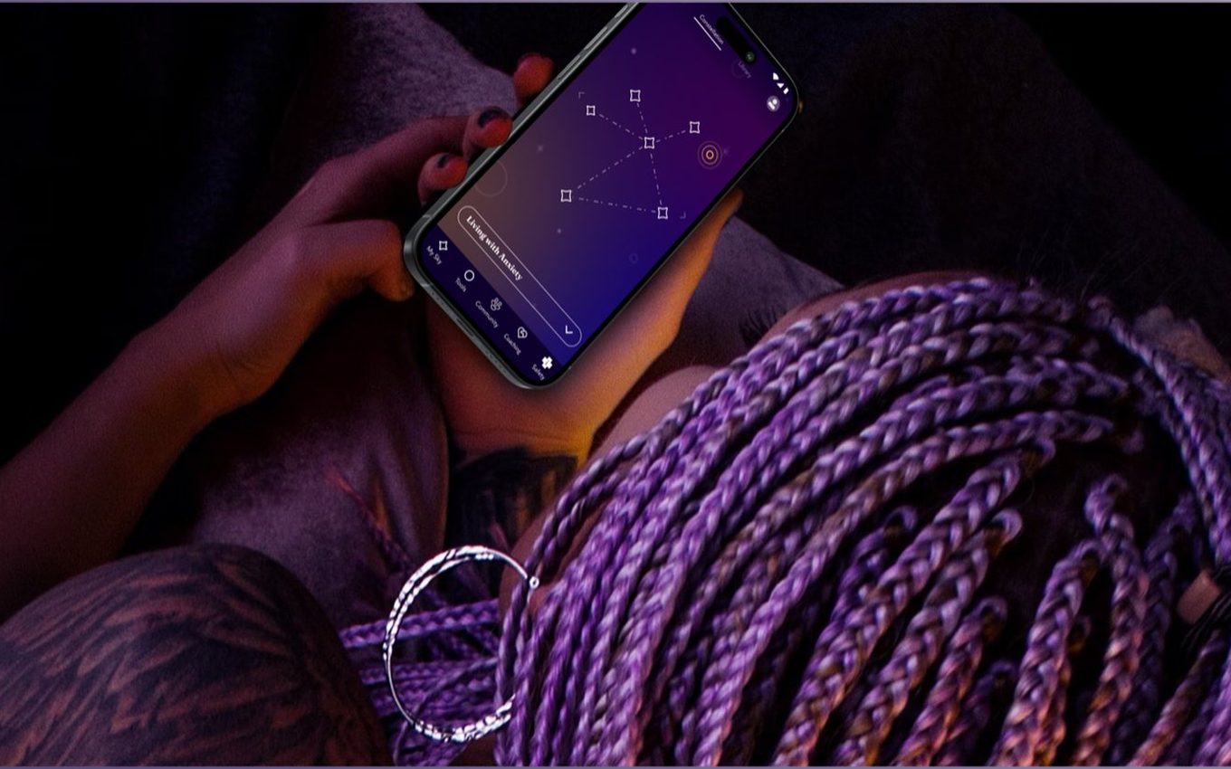 A young person holding a phone showing the Soluna app at night